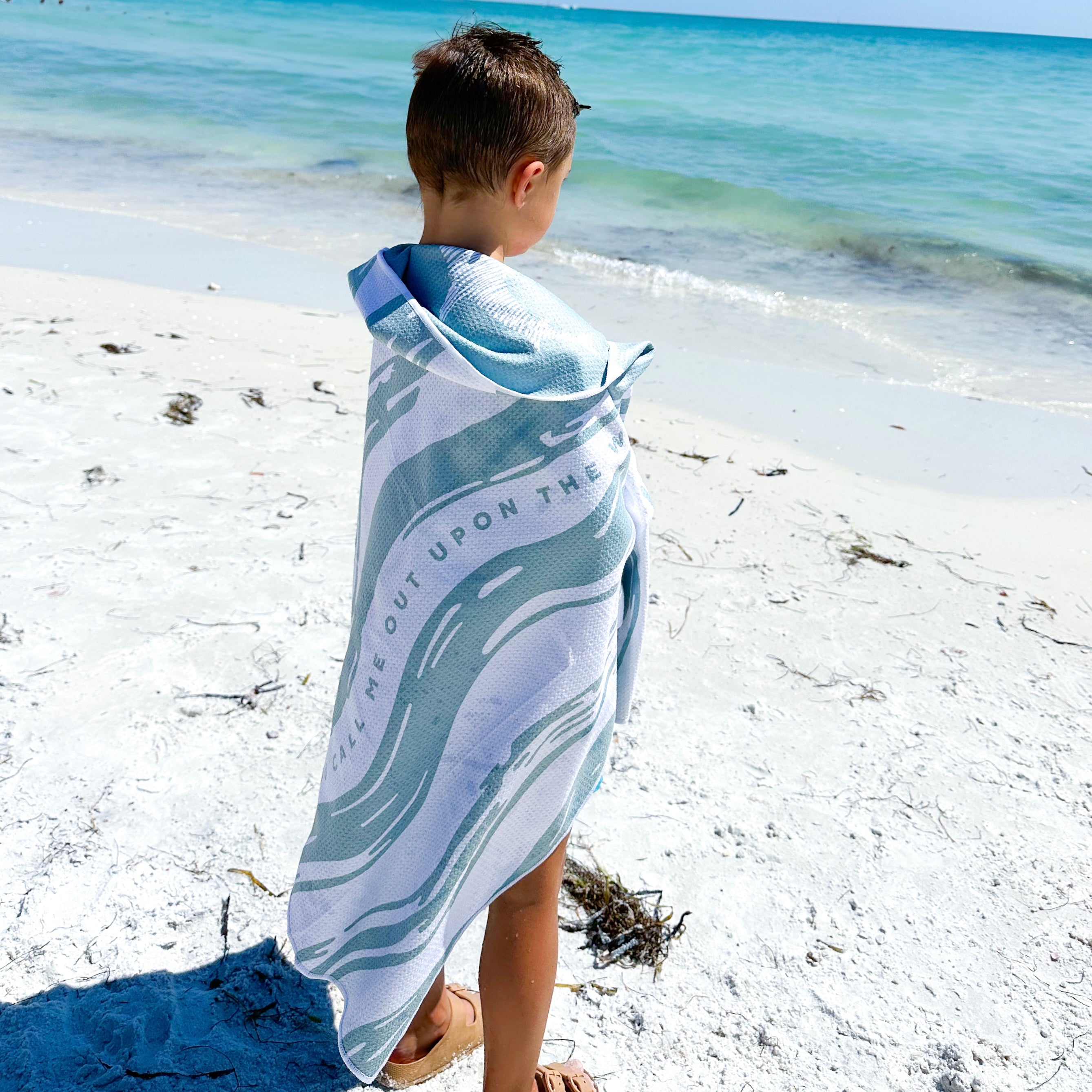 Boy wrapped in towel on beach